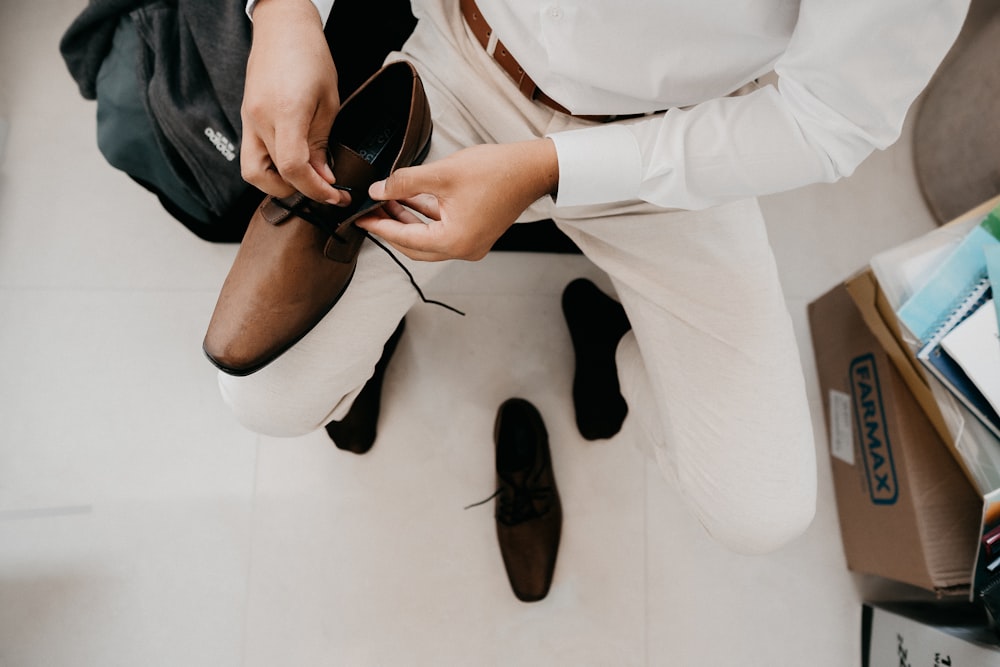 person in white pants and black leather shoes