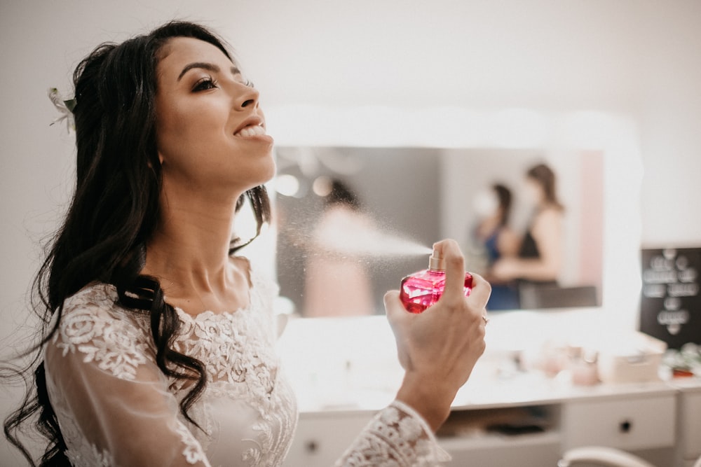 woman in white lace floral dress holding pink heart ornament