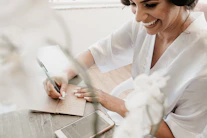 woman in white dress shirt writing on white paper