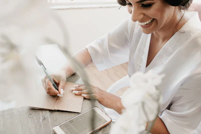 woman in white dress shirt writing on white paper