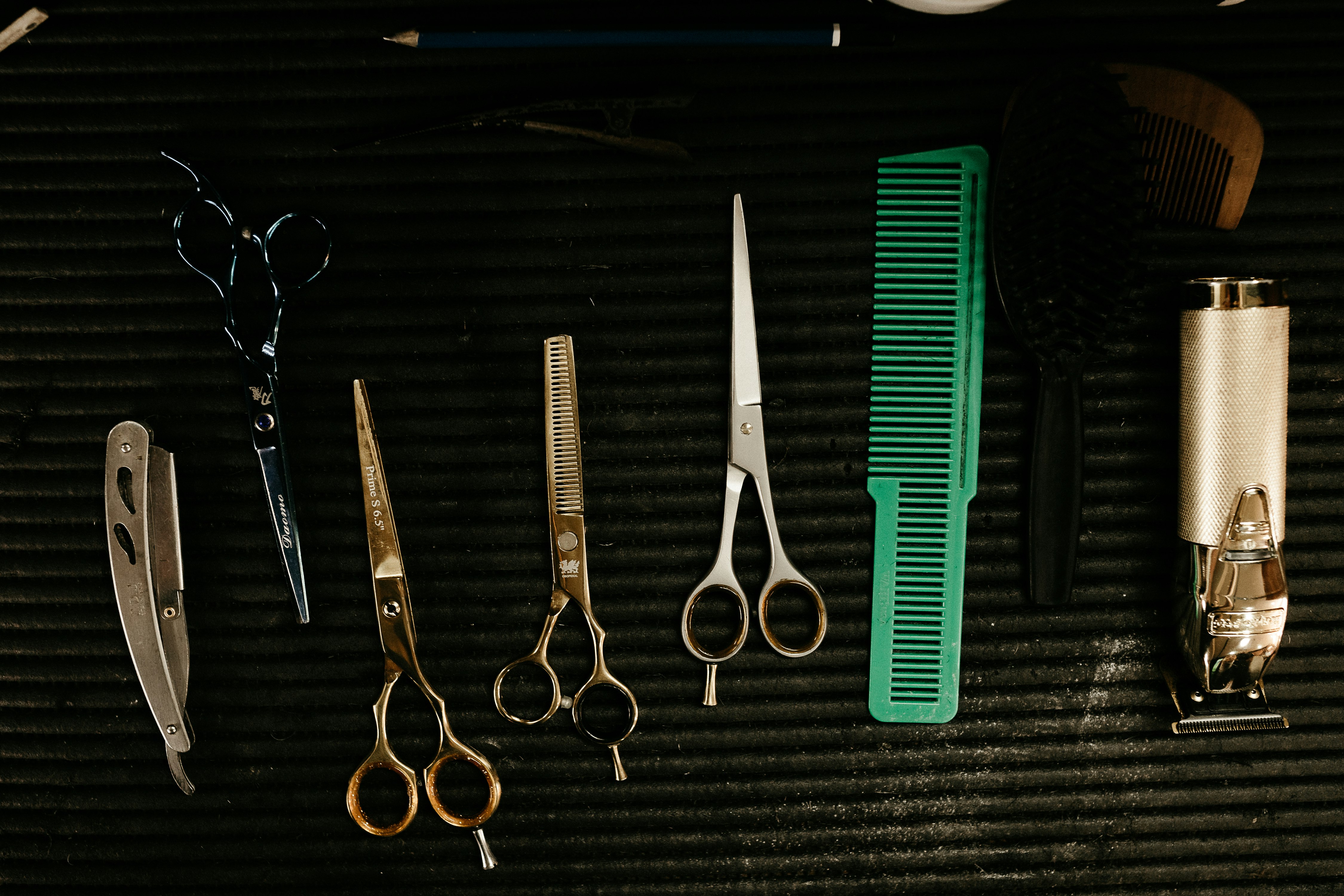 black handled scissors beside green hair comb and black handled scissors