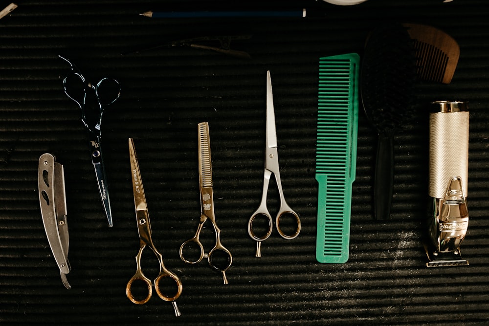black handled scissors beside green hair comb and black handled scissors