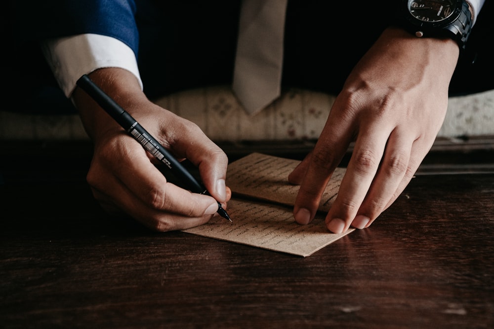 person writing on brown wooden table