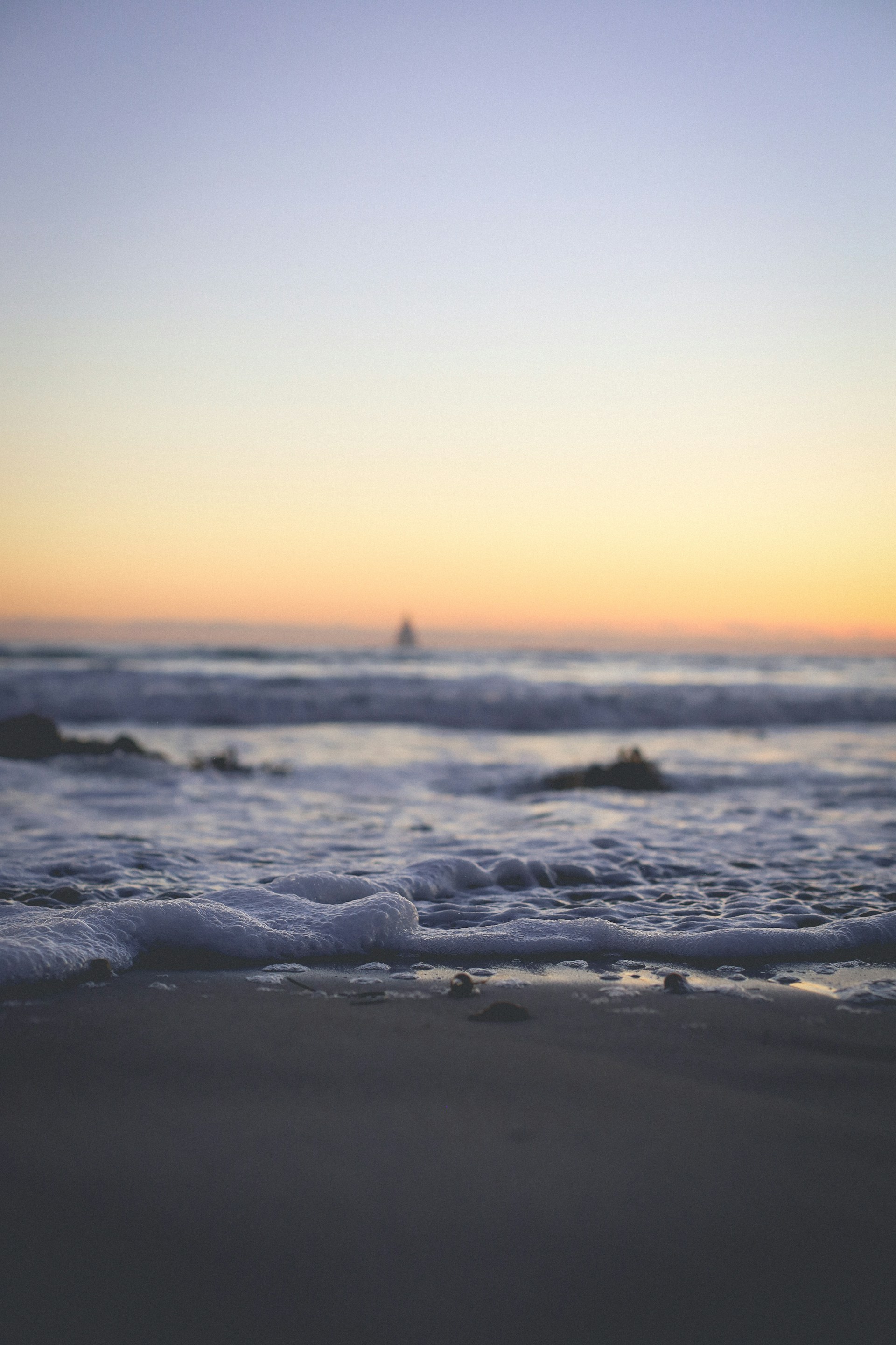 ocean waves crashing on shore during sunset