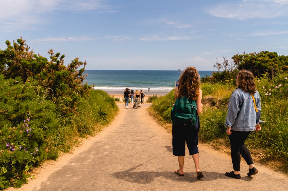 mulher no vestido azul da manga comprida que anda na praia de areia marrom durante o dia