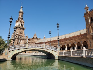 brown concrete bridge over river under blue sky during daytime