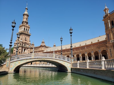 brown concrete bridge over river under blue sky during daytime