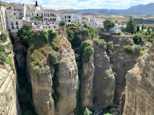 White concrete building on brown rocky mountain during daytime — Ronda, Spain