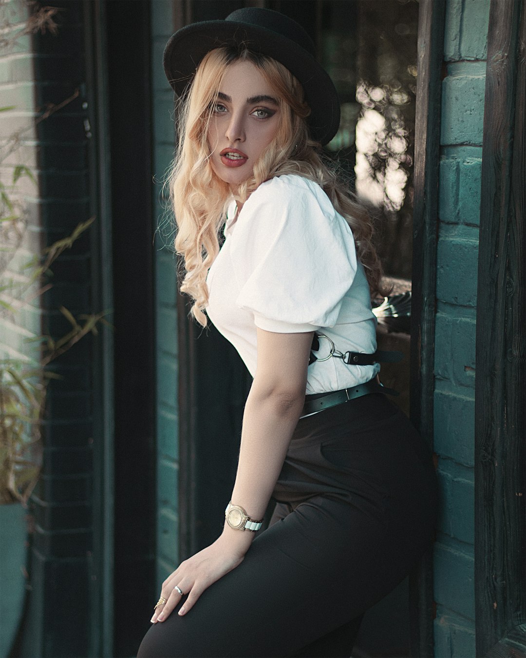 woman in white shirt and black skirt sitting on green wooden window