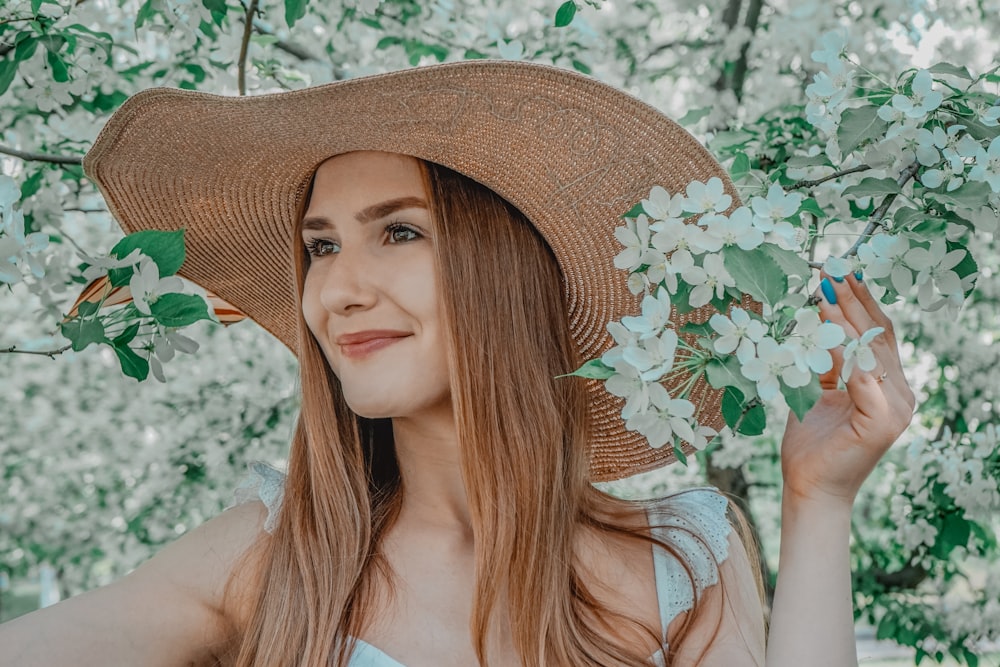 茶色の日よけ帽と白い花柄のノースリーブトップスを着た女性
