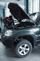 man in black jacket standing beside black car
