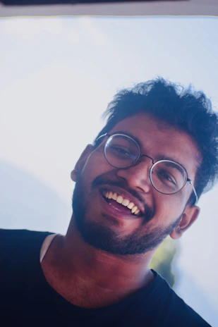 Close-up of a cheerful young man with glasses, showing enthusiasm and friendliness.