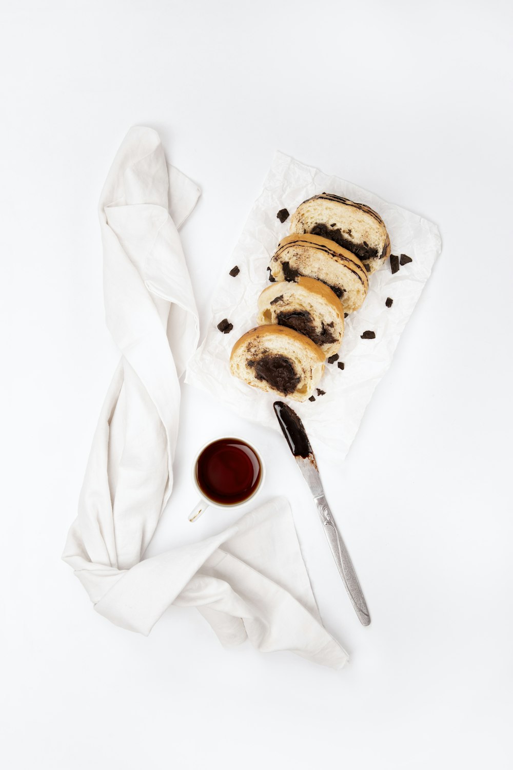 bread on white paper beside red liquid in clear drinking glass