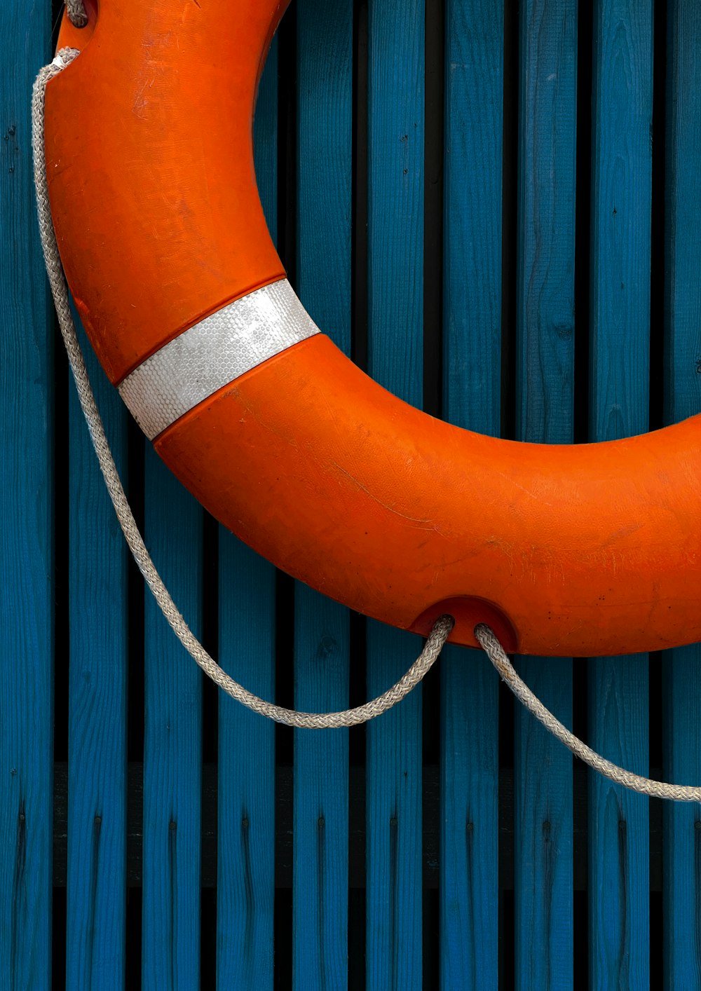 orange and black life buoy on blue wooden fence