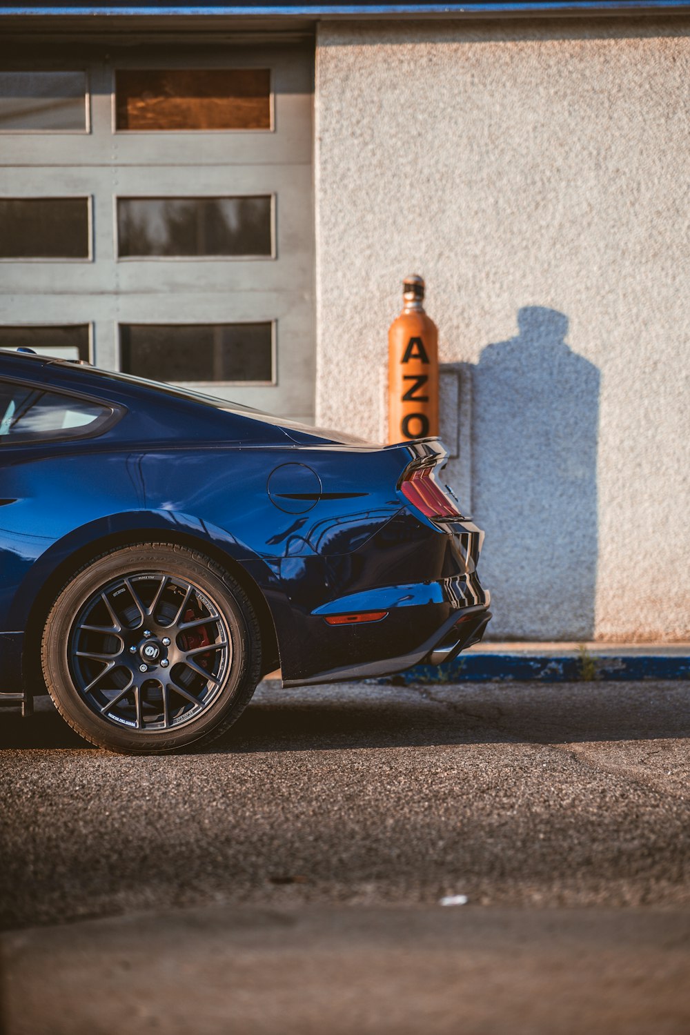 Blauer Porsche 911 tagsüber in der Nähe eines weißen Betongebäudes geparkt