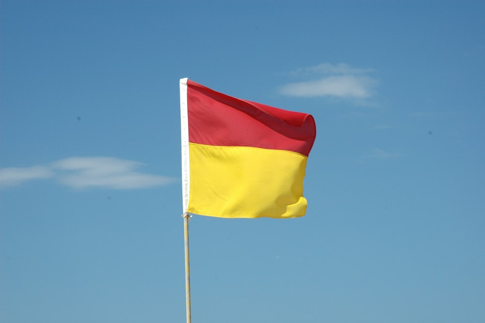 red and yellow flag under blue sky during daytime