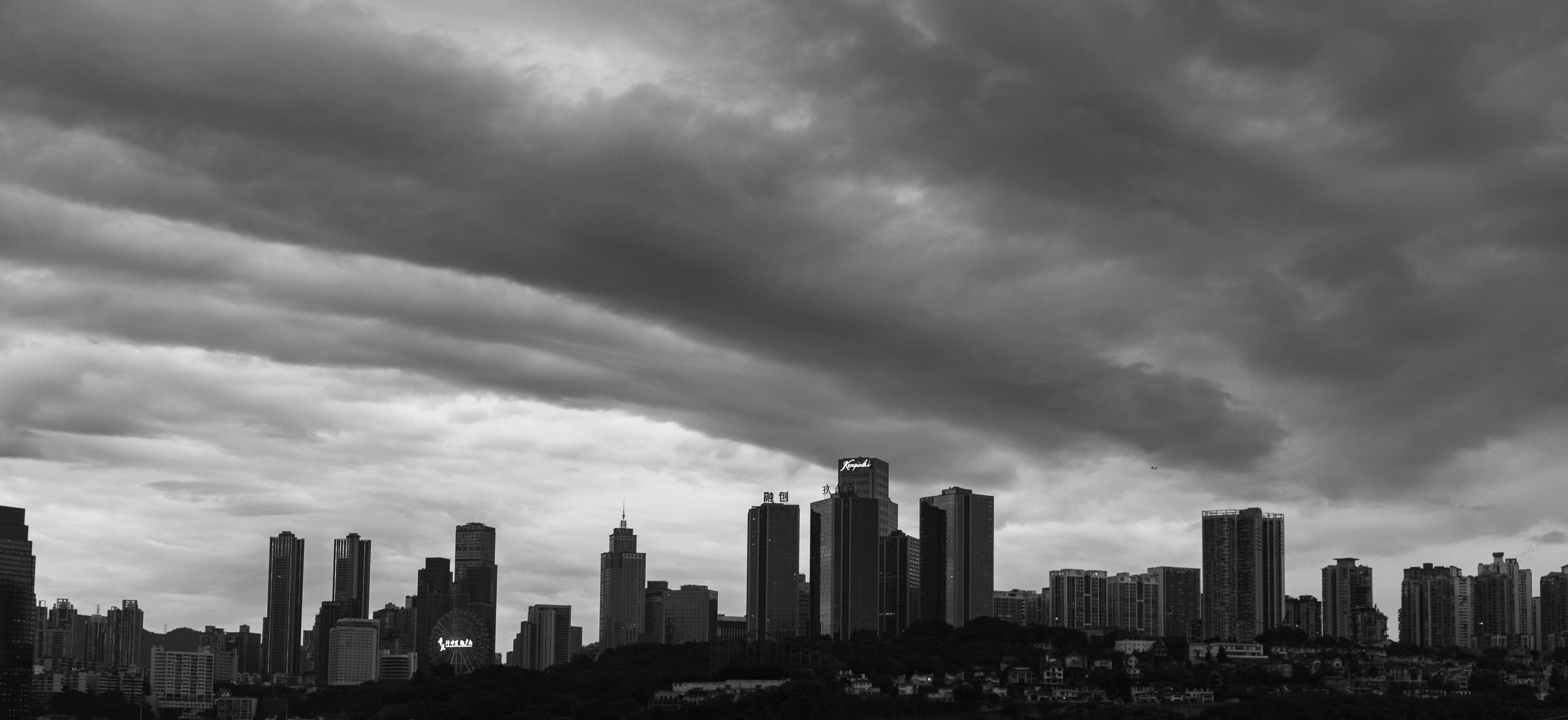 grayscale photo of city buildings under cloudy sky