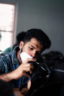 man in blue denim jacket holding black dslr camera