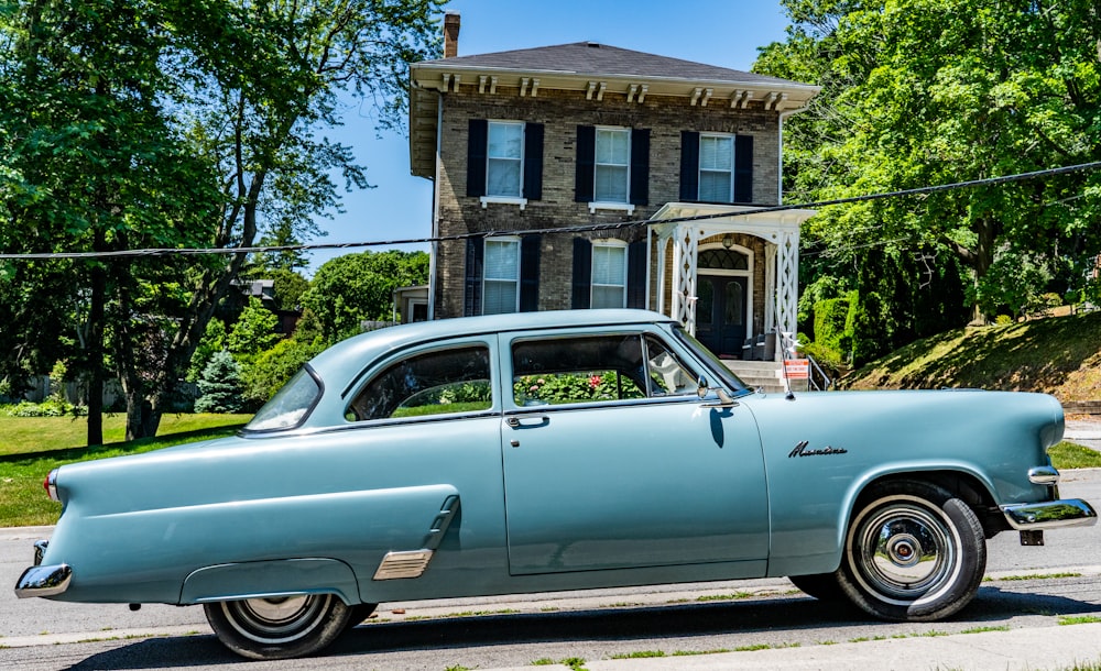 white classic car parked beside brown concrete building during daytime