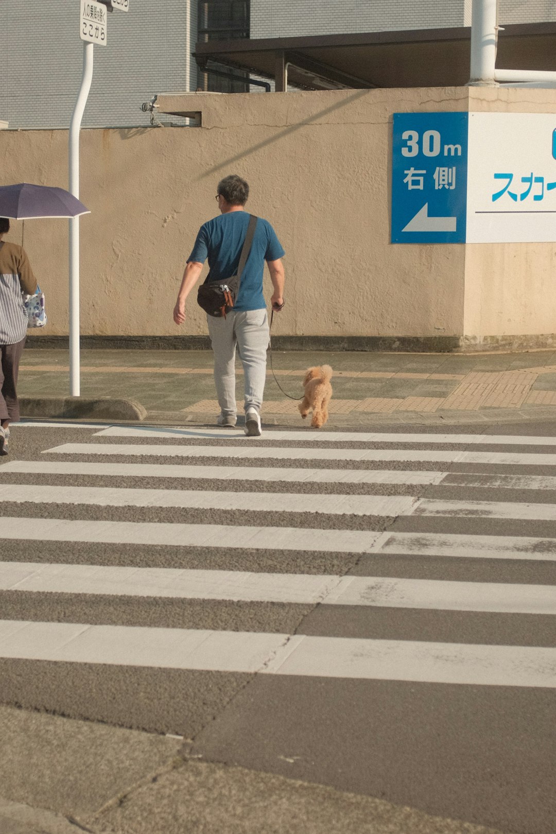 man in blue crew neck t-shirt and blue denim jeans walking on pedestrian lane during