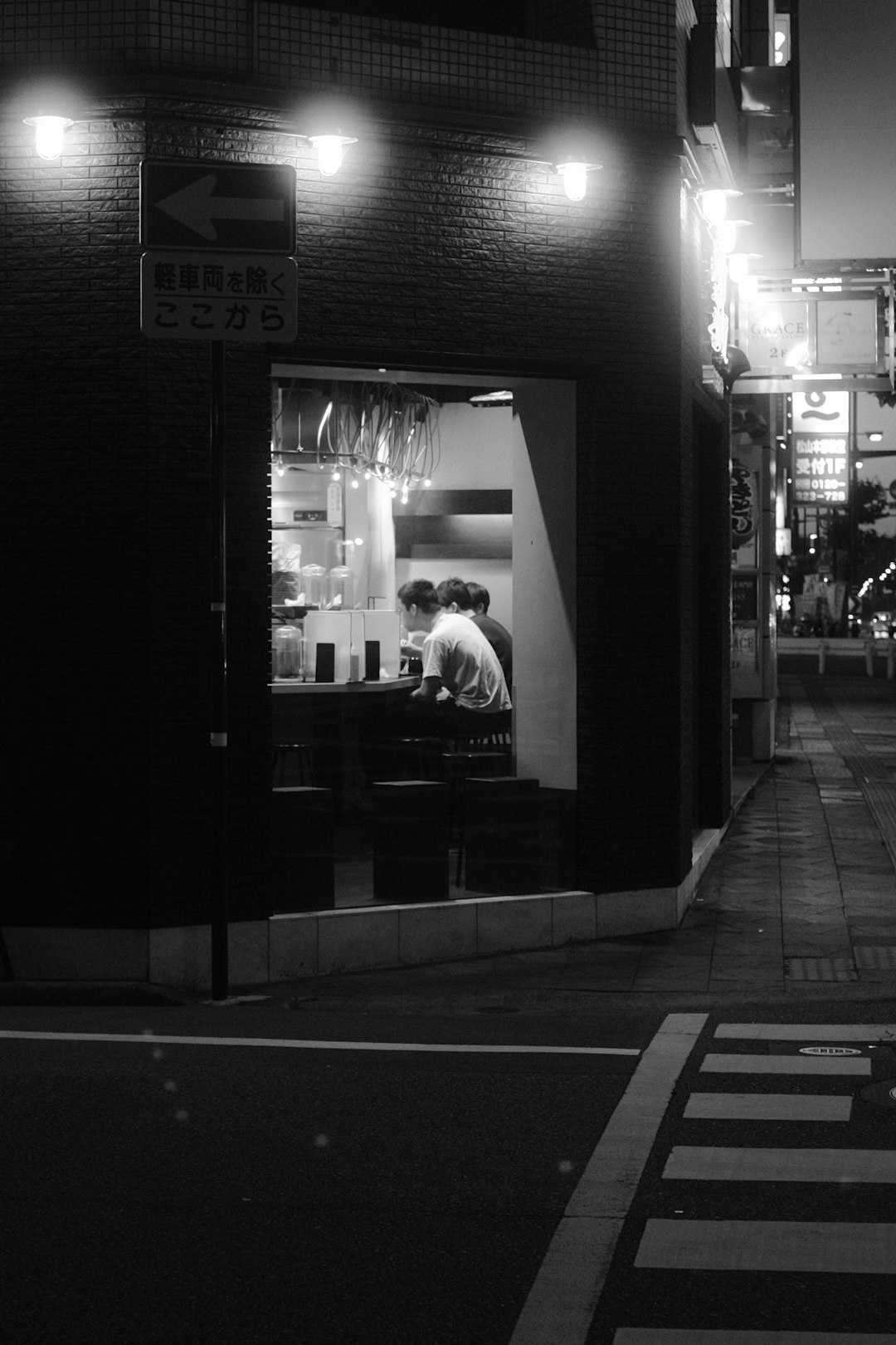 grayscale photo of man and woman standing in front of store