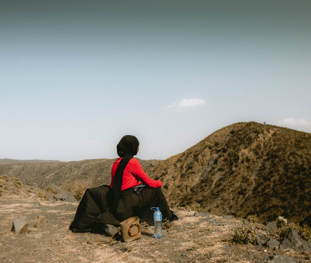 man in black jacket sitting on brown rock during daytime