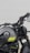 A close-up view of a motorcycle showcasing the handlebars and fuel tank. The motorcycle is designed with sleek black and gray colors, featuring the brand name 'Benelli' on the chrome badge. Yellow accent stripes add a contrasting element to the design. The focus is on the mechanical and design aspects of the motorcycle.