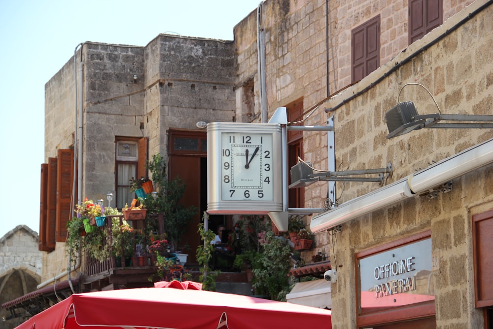 brown wooden analog clock on brown concrete building during daytime