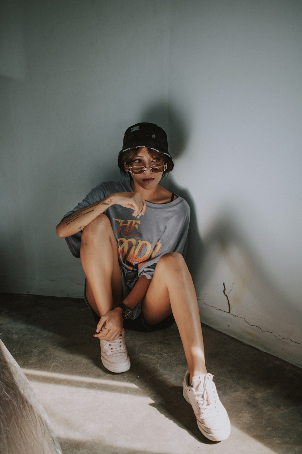 woman in gray tank top and black fitted cap sitting on floor