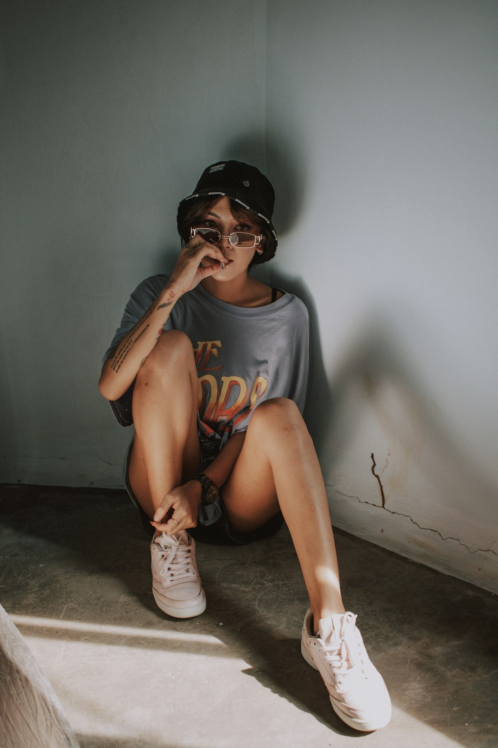 woman in gray crew neck t-shirt and black cap sitting on floor