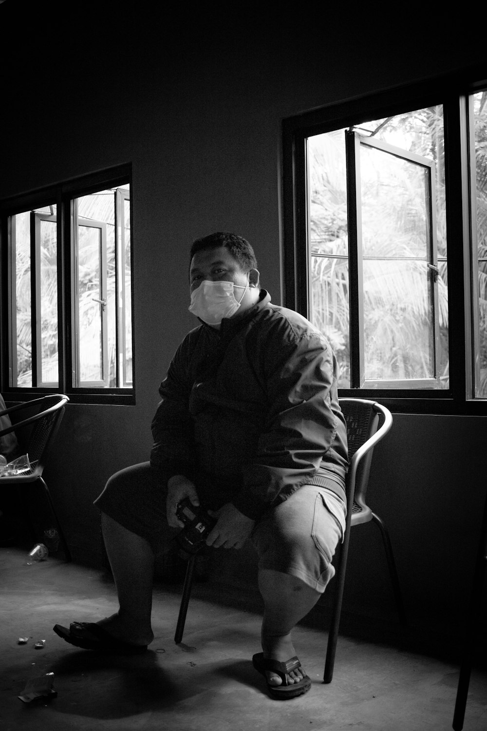 grayscale photo of man sitting on chair