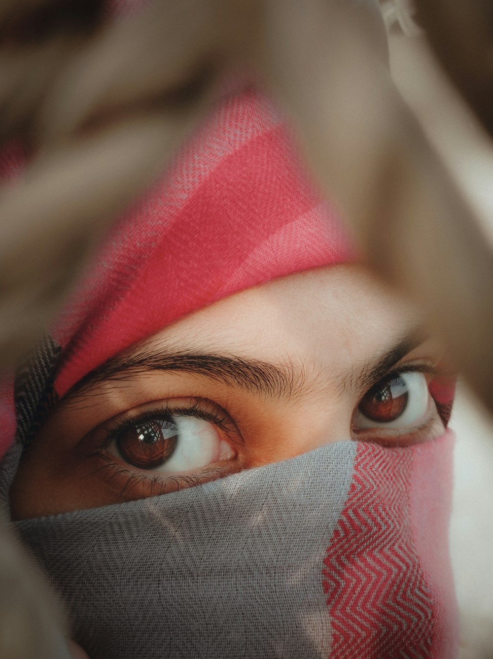 woman in red hijab covering her face with her hand
