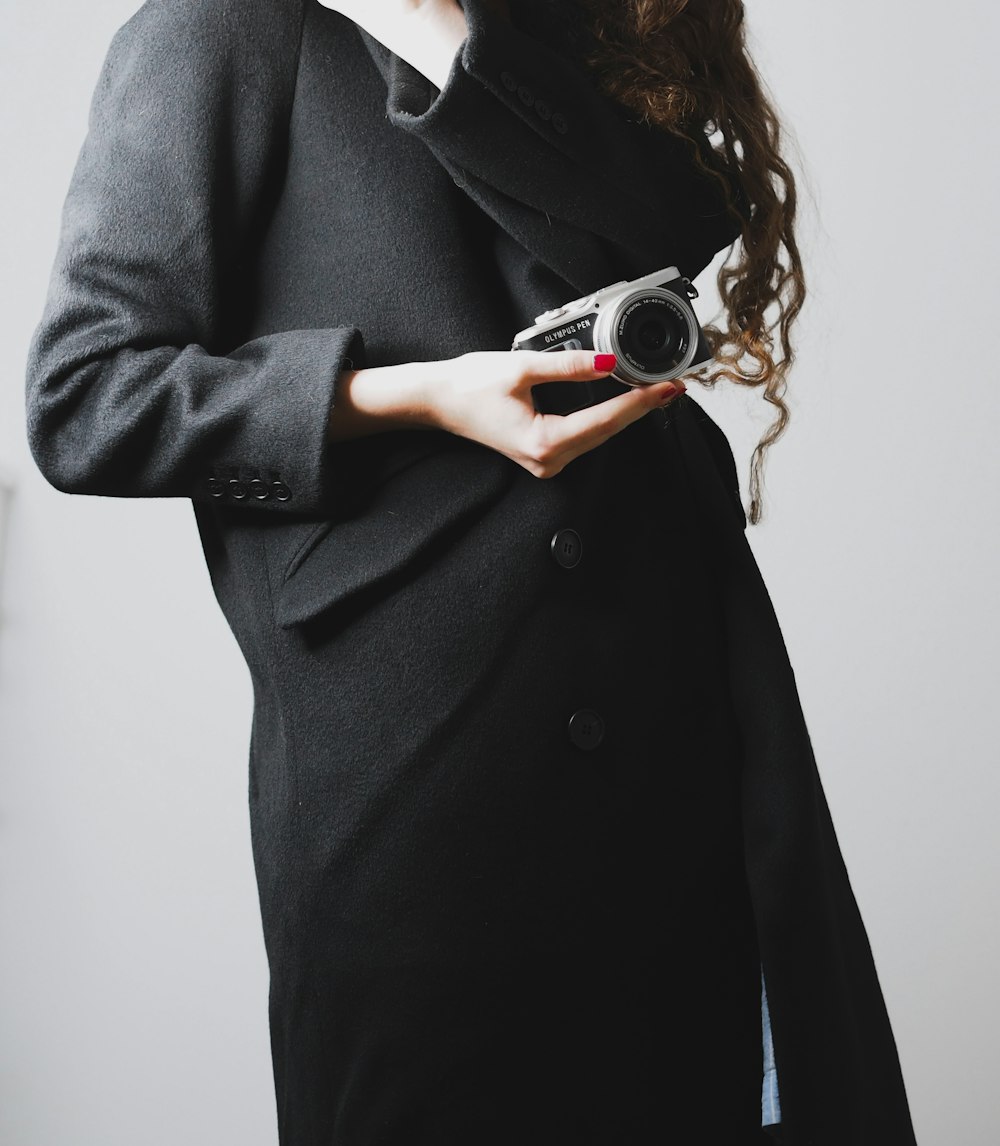 woman in black coat holding silver and black camera