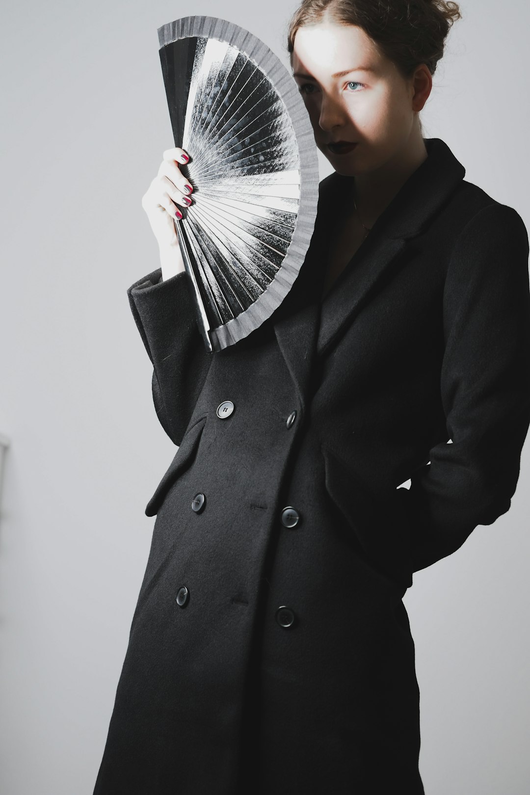 man in black coat holding fan