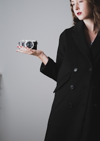 A model wearing sleek black gloves while holding a vintage camera.