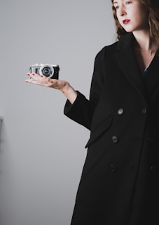 A model wearing sleek black gloves while holding a vintage camera.