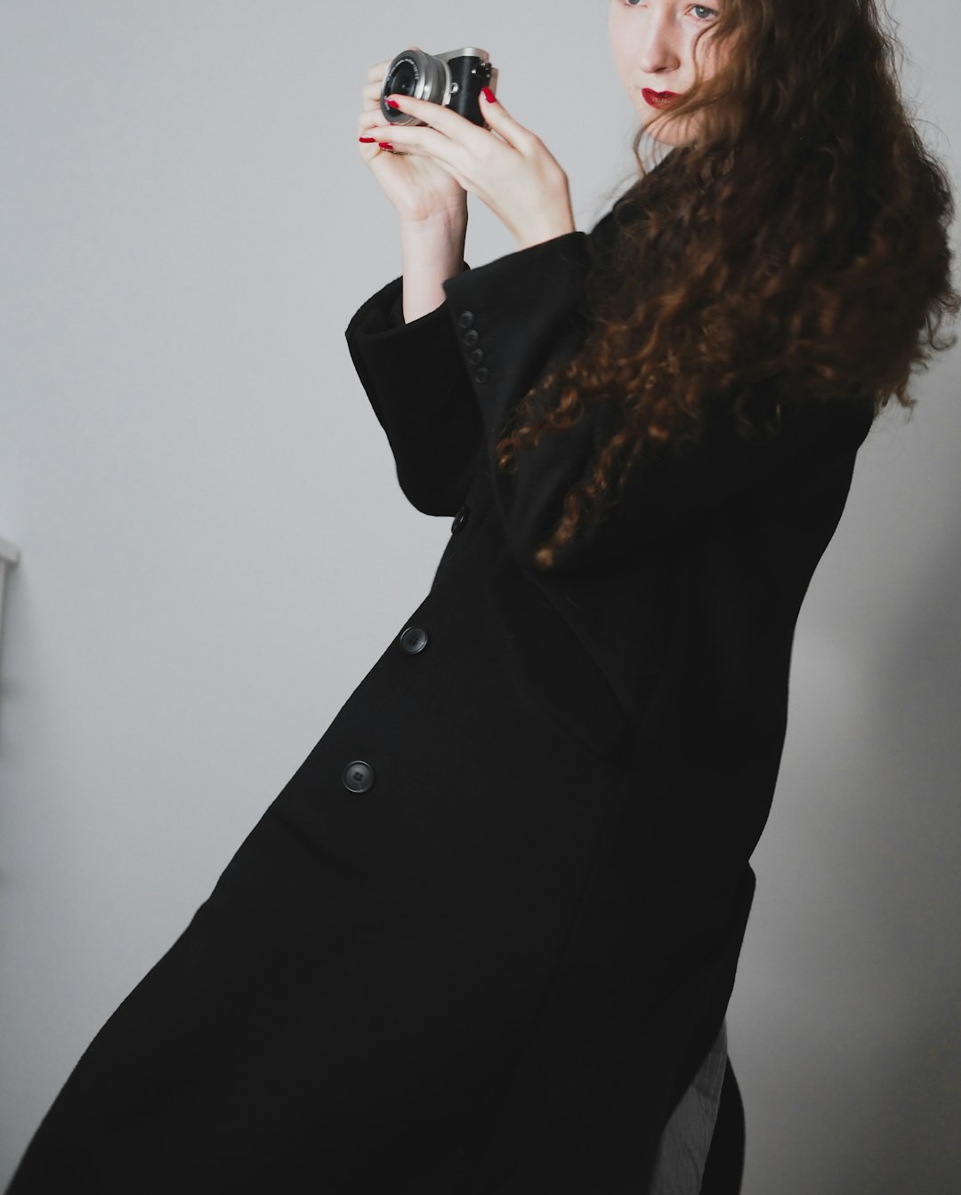 woman in black coat standing near white wall