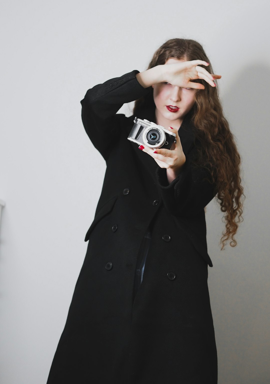 woman in black coat holding gray and black camera