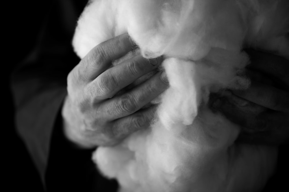 person holding white cotton in grayscale photography
