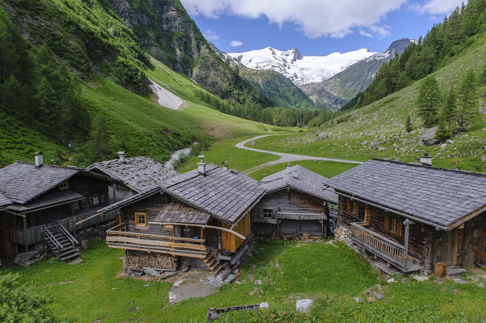 casa di legno marrone sul campo di erba verde vicino alle montagne verdi durante il giorno