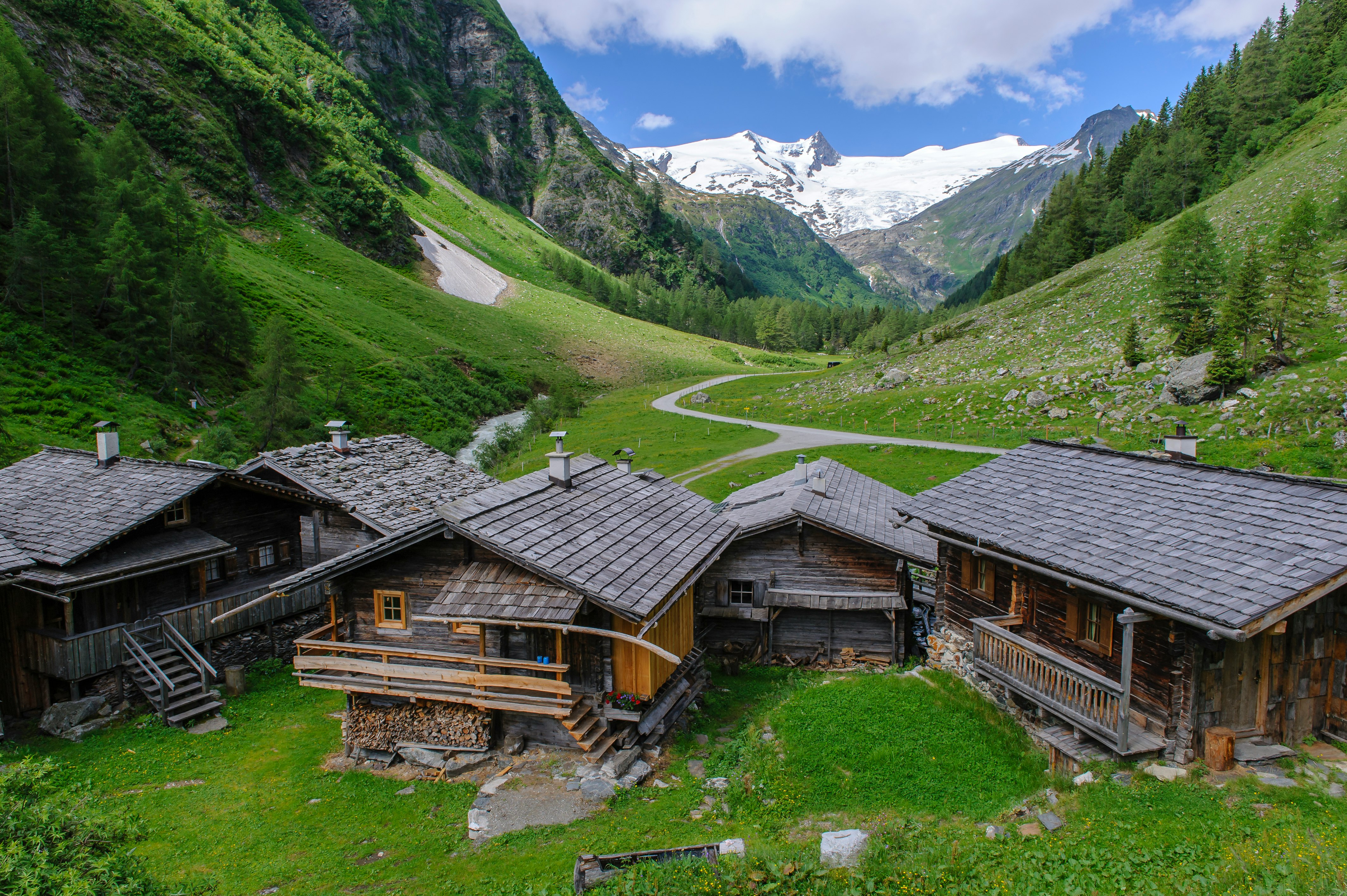 brown wooden house on green grass field near green mountains during daytime