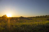 A serene sunset casting warm light over a quiet, open land area.