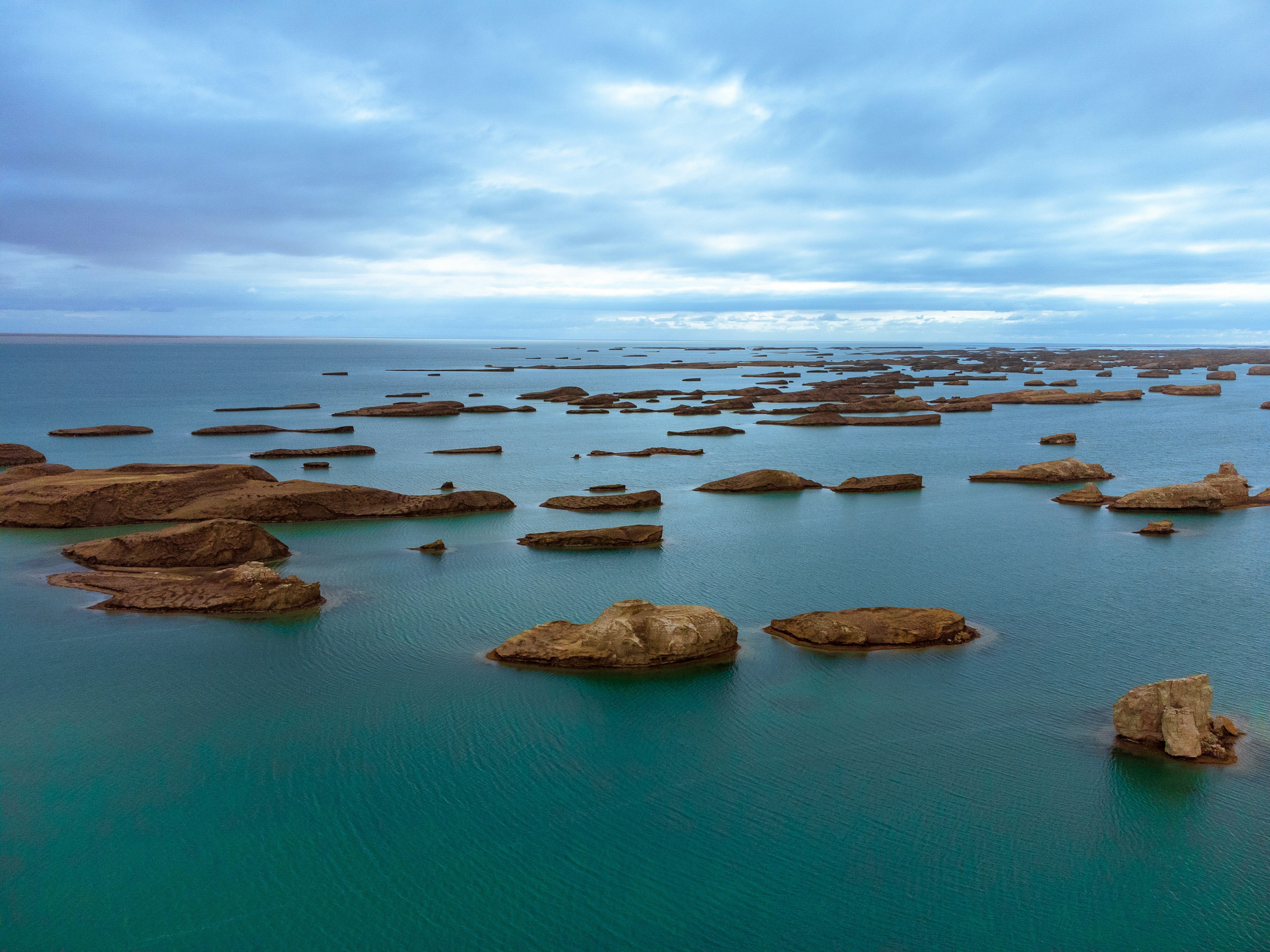brown rocks on blue sea under white clouds and blue sky during daytime