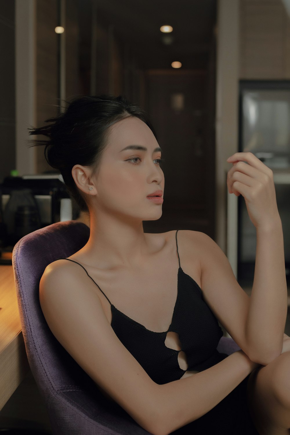 woman in black tank top sitting on brown wooden chair