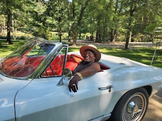 Smiling customer standing next to their polished car in a driveway.