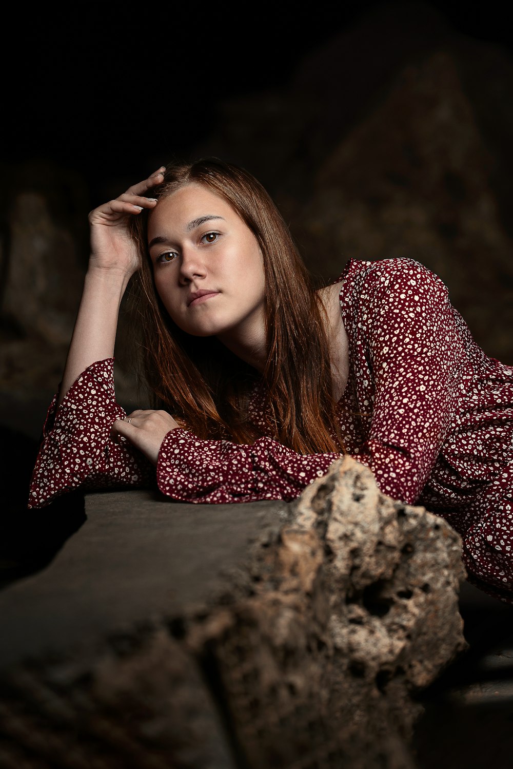 woman in red and white polka dot long sleeve shirt lying on brown rock