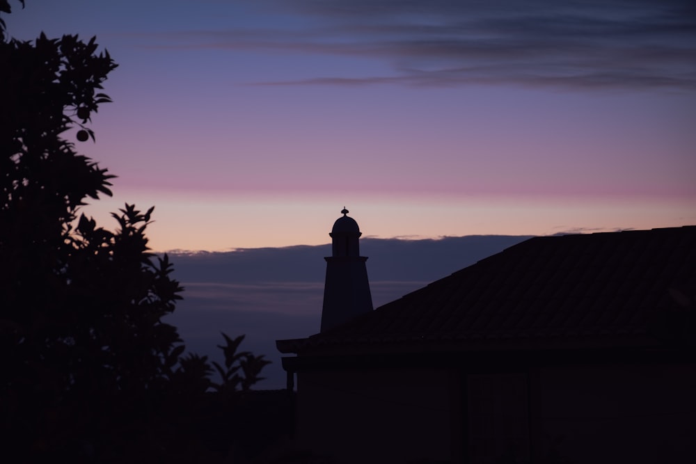 silhouette of man standing on roof during sunset