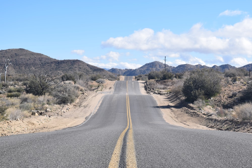 gray asphalt road between brown grass field during daytime