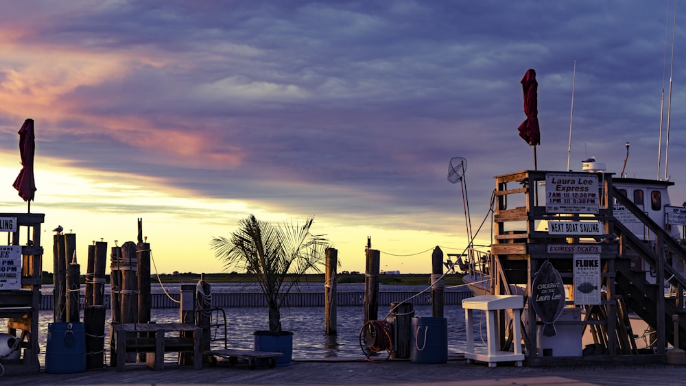 white and blue boat on dock during sunset