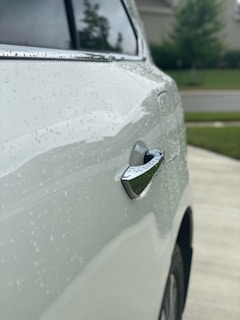 Close-up of a clean car exterior reflecting sunlight in a residential driveway